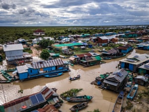 An aerial view of a boat moving between floating houses