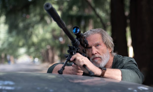 Jeff Bridges in woodland aiming a long-range rifle up high