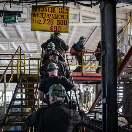 Coal miners step out of the elevator and head toward the changing rooms and showers