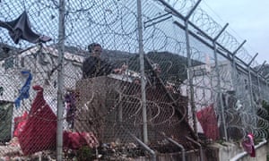 A man peers out from behind a fence surrounding the overcrowded reception facility on the Greek island of Samos