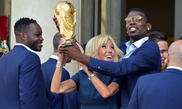 The French first lady, Brigitte Macron, holds up the World Cup trophy with Paul Pogba, at the Élysée Palace in Paris.
