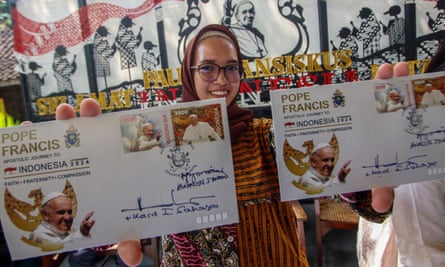 A woman shows samples of a new series of stamps ahead of the visit by Pope Francis to Jakarta