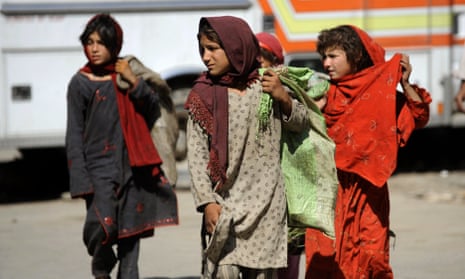 Pakistani girls walk with sacks filled with scavenged garbage in Islamabad