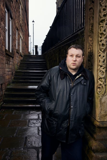 Daniel Lavelle in a black jacket, leaning against a wall in an alleyway in front of a flight of stairs