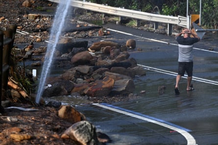 Residents navigate through debris and a burst water main which cut Lawrence Hargrave Drive at Coalcliff on Saturday.