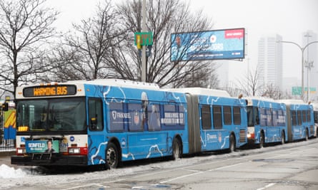 At least four long rows of bright blue buses line the snowy pavement.