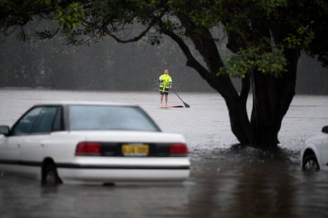 Man on a paddleboard flanked by cars in a flooded Campbell Parade, Manly, Sydney