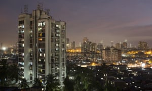 A high-rise residential tower is seen next to shanties in Dharavi, one of Asia’s largest slums, on March 18 2015. In Mumbai, the windows of new high-rise apartment blocks, old low-rise residential buildings and shantytown shacks portray the disparity in living conditions and incomes in the Indian city.