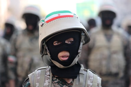 A child in military clothes with their face covered by a balaclava