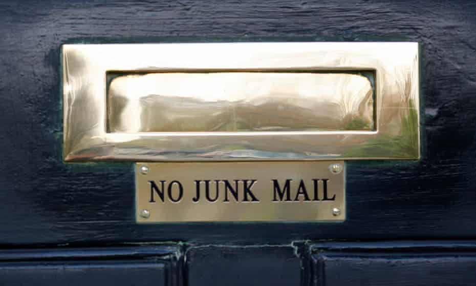 A sign saying No Junk Mail under the letterbox of a front door of a house