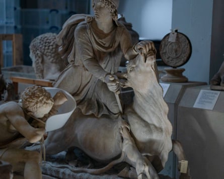 A sculpture of a man sitting on a animal, holding its mouth