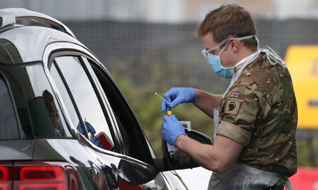 A soldier tests a key worker at a drive-through centre at Glasgow airport