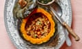 Whole roast pumpkin stuffed with herby pearl barley, chestnut, gorgonzola, garlic and chilli on an oval plate with a knife and spoon