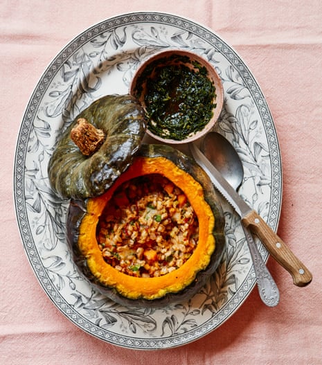 Whole roast pumpkin stuffed with herby pearl barley, chestnut, gorgonzola, garlic and chilli on an oval plate with a knife and spoon