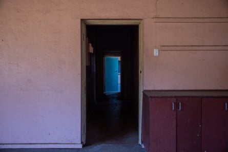 A door in a pink wall opens to another darkened corridor