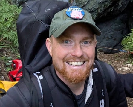 Man with a ginger beard, wearing a backpack, smiles at the camera
