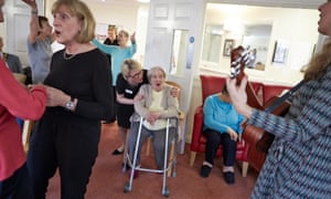 Care workers and elderly residents at a music therapy group session in Oxfordshire