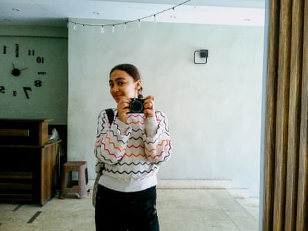 Toleen smiles shyly in the mirror behind the camera