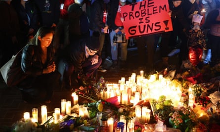 People attend a candlelight vigil for victims of a deadly mass shooting at a ballroom dance studio, as a person holds a sign reading “The Problem Is Guns!”, on January 24, 2023 in Monterey Park, California.