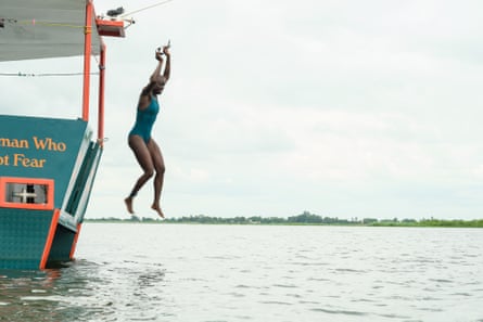 A young African woman jumps off a boat into a wide river