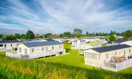 Static caravans in an attractive grassy site, each with their own fenced-off patios, under a blue sky