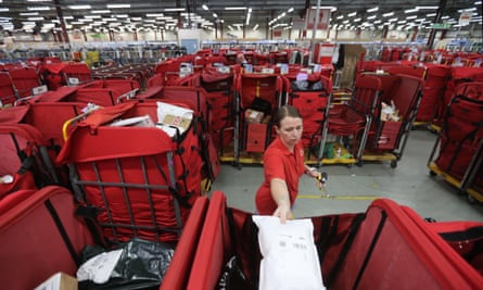 A postal worker sorting parcels at a big sorting office