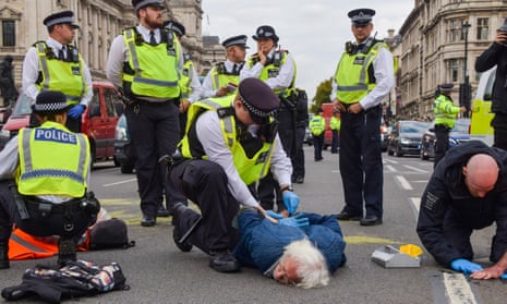 Police officers arrest an Insulate Britain activist, Parliament Square, London, October 2022.