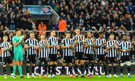 Newcastle football team stood in a line clapping on the pitch
