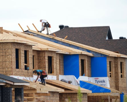 Row of houses under construction with builders on roof