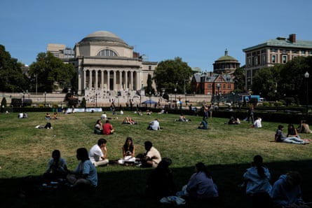 people seated on lawn in front of building with columns and dome