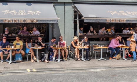 Customers relaxing, eating and drinking inside and outside a bar and brasserie in London