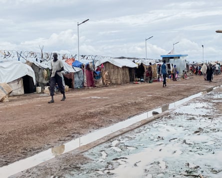 People walk past rows of tents in a camp for displaced people