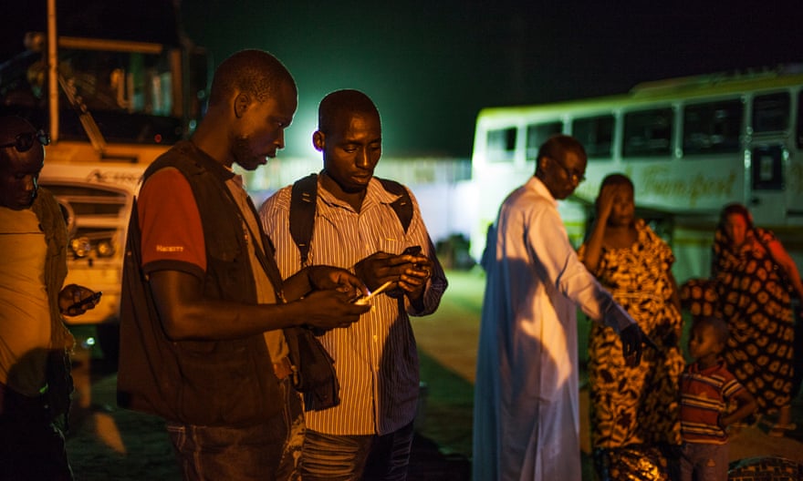 Two migrants from Burkina Faso exchange telephone numbers upon arriving to Agadez, Niger. This is the final stop of commercial buses. The journey from here on will be through the help of a network of smugglers who drive small pick-up trucks.