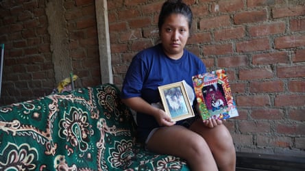 A sad young woman holds family photos