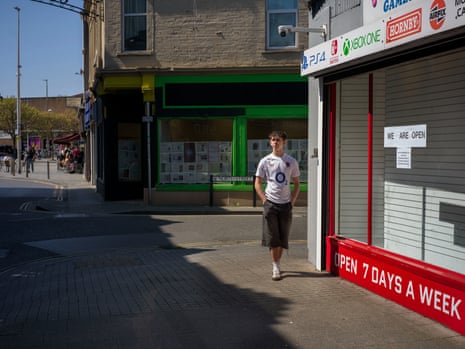 A man walks past a shop with an empty window in a quiet street