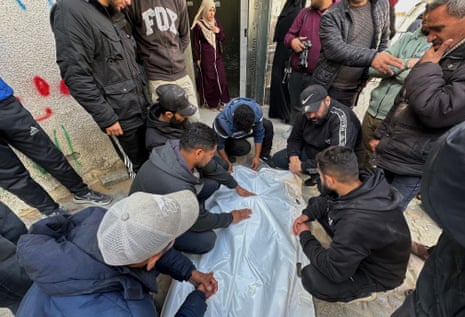 At Al-Shifa hospital, Palestinian people mourn over the body of someone killed in an Israeli airstrike.