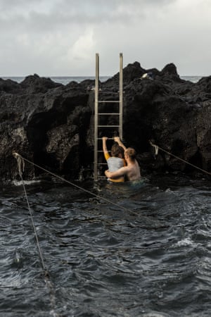 Ponta da Ferrari, Azores, A simple metal ladder leads to a little cove of warm water. Gulls and other seabirds wheel and whirl above. Heat ebbs and flows with each set of waves. Ropes hover above the water’s surface, and people hold tight. The ropes provide bathers stability as the waves move bodies like strands of kelp. Swimmers audibly gasp and cheer as each wave approaches. It feels daunting, being at the edge of nature like this. The waves move your buoyant body and reacquaint you with the push and pull of the sea.