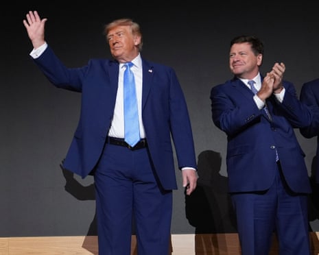 Donald Trump waves next to a man clapping
