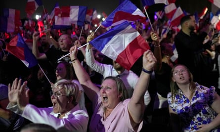 Women in a crowd cheer, hold their arms in the air, and wave French flags