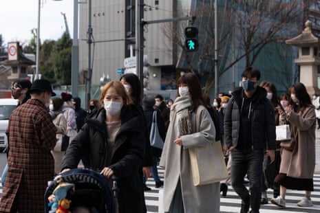 Passersby wearing protective face masks walk on a street in Tokyo, Japan on 17 January, 2022.