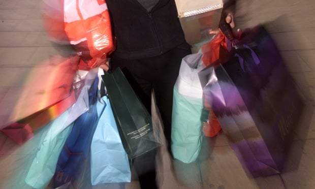 A soft-focus close-up of a woman carrying colourful shopping bags