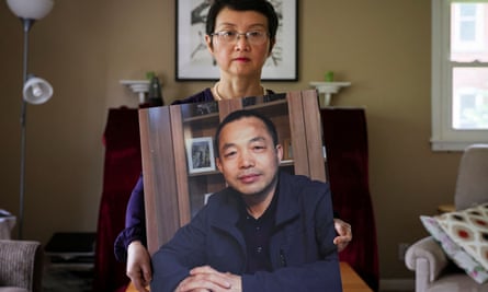 Luo Shengchun, the wife of Ding Jiaxi, poses with a photo of her husband at her home in Alfred, New York, last year