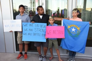 People hold signs and the Nevada state flag during a vigil at Las Vegas City Hall