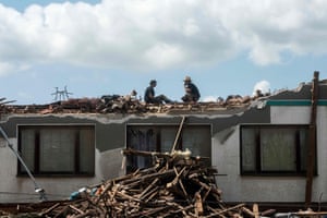 South Moravia, Czech Republic: Two men clean sit on a damaged roof after a tornado tore through several Czech villages and towns.