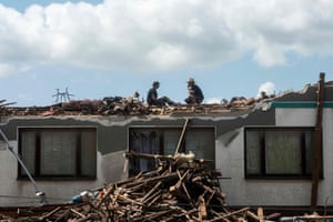 South Moravia, Czech Republic: Two men clean sit on a damaged roof after a tornado tore through several Czech villages and towns.