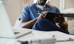 Doctor in scrubs using digital tablet in clinic<br>EJRT19 Doctor in scrubs using digital tablet in clinic