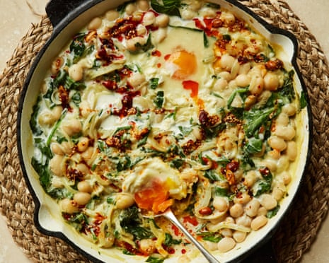 Chilli eggs with miso beans and spinach in a cast iron skillet on a straw mat.