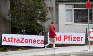 A man walks past signs for AstraZeneca and Pfizer outside a doctor’s surgery in Sydney