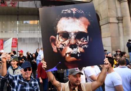 Anti-lockdown protester in a crowd holding a sign which is a defaced image of Dan Andrews