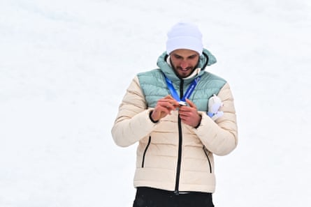 Nikita Filippov, wearing a neutral tracksuit, checks out his silver medal during the ceremony.